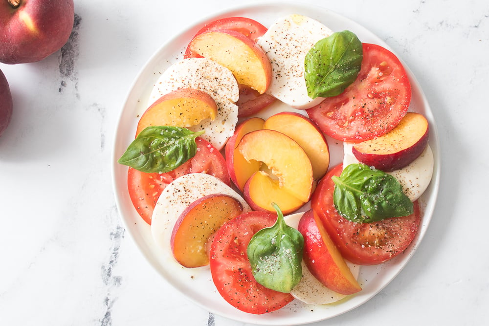 layers of freshly sliced mozzarella, tomatoes, peaches, basil, olive oil salt and pepper