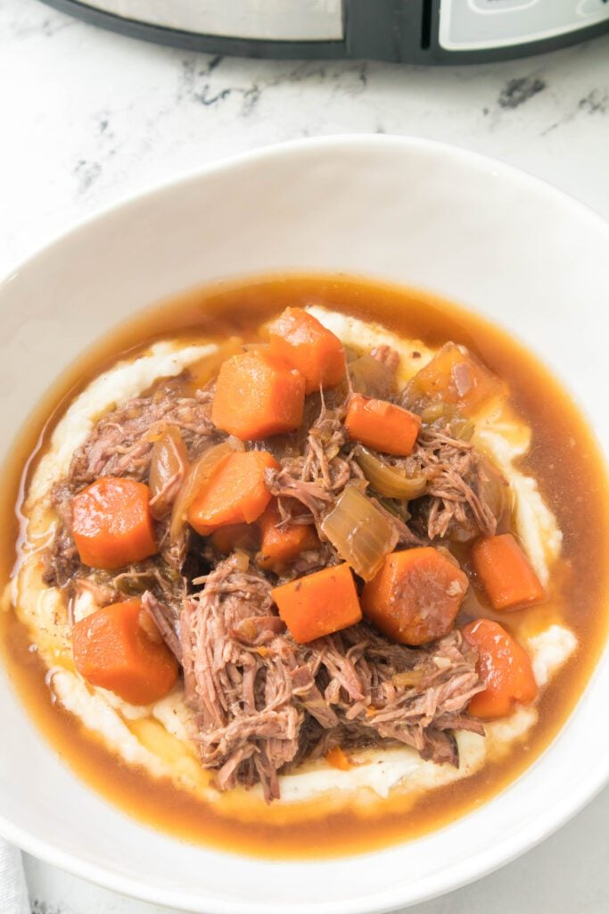 close up overhead shot of pot roast over mashed potatoes