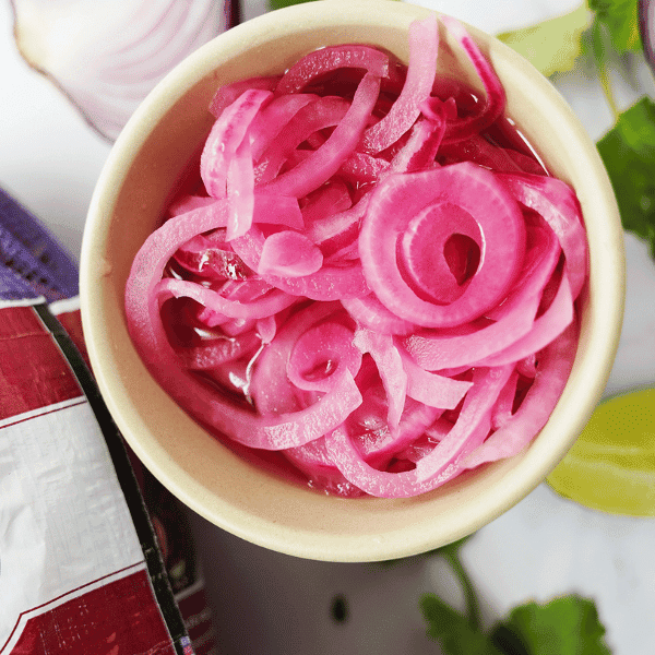 Pickled Red Onions in bowl with bag of onions