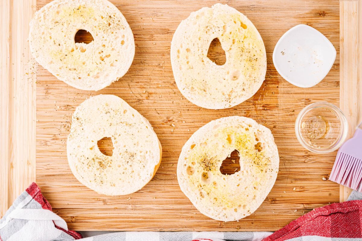 Halved bagels with olive oil and seasoning on top.