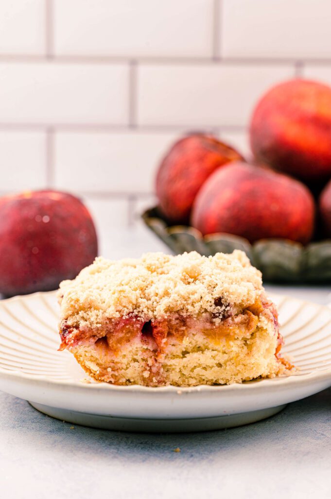 slice of coffee cake with peaches in the background