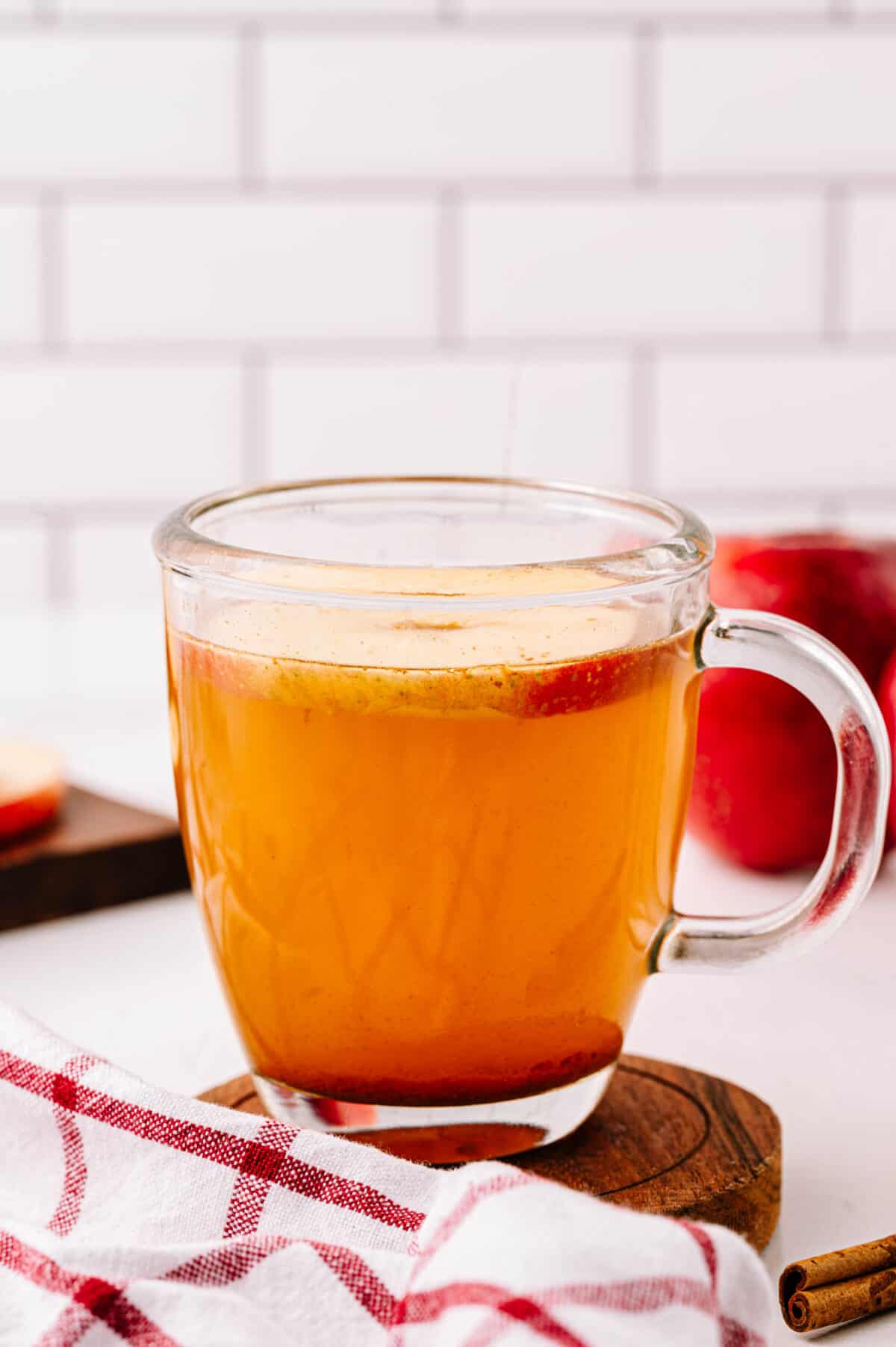 vertical head on shot of glass mug with hot cider apple toddy and apple slice ring