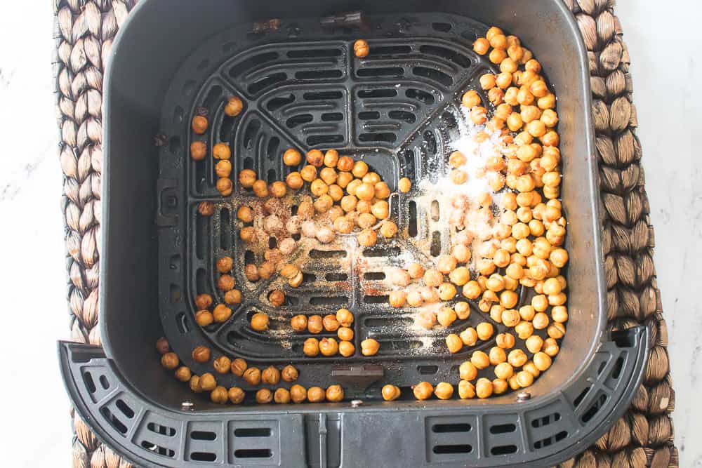 spices on top of the chickpeas in the air fryer basket