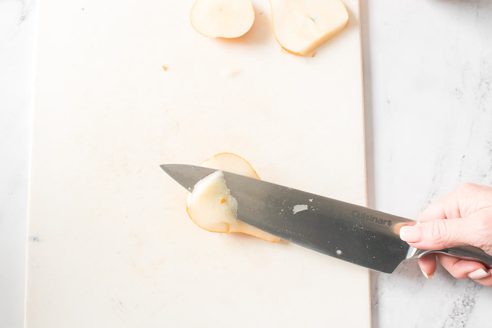 pear on cutting board cut in half with knife removing pit