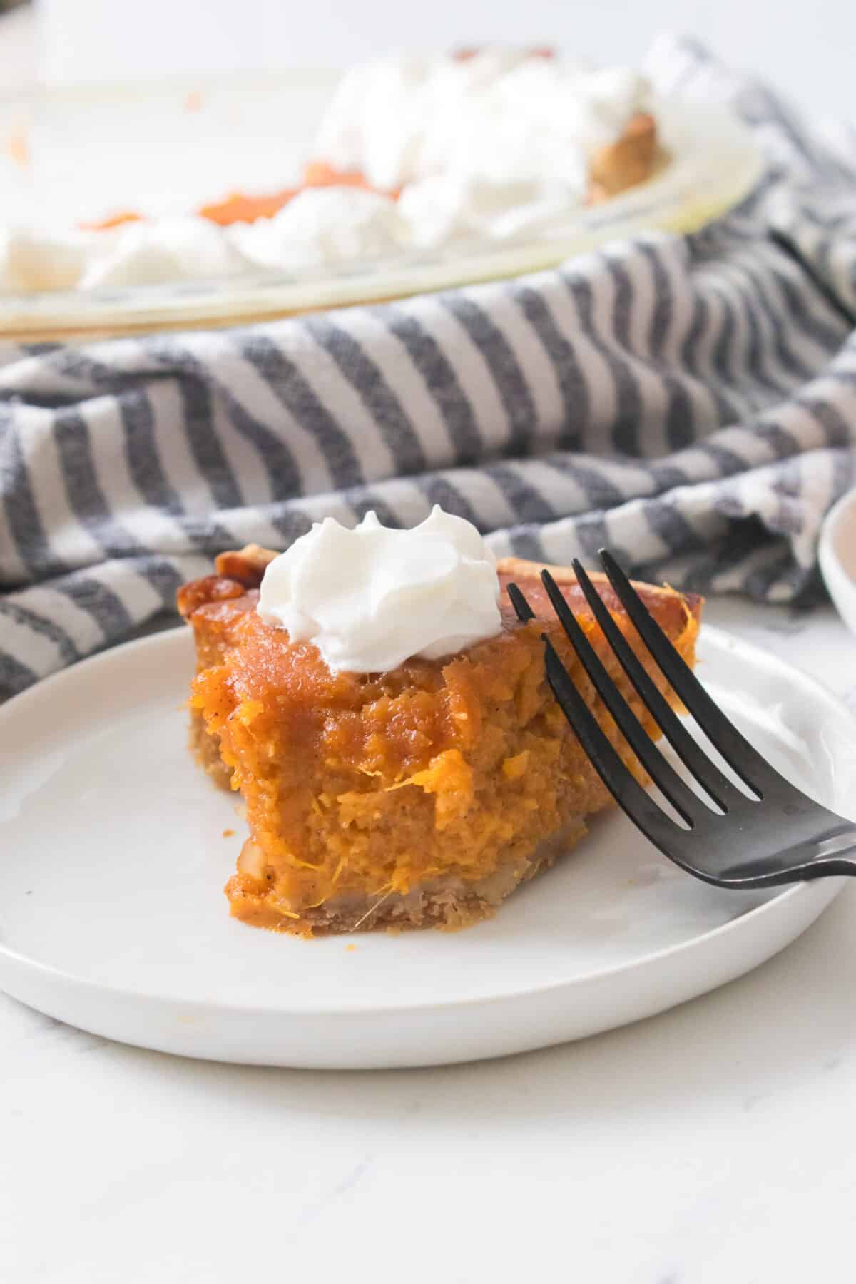 sweet potato pie with bite taken out of it on white plate and fork