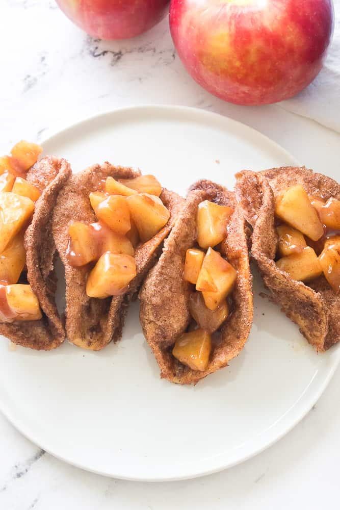 vertical image of apple pie filling in taco shells that have been coated in butter, cinnamon and sugar