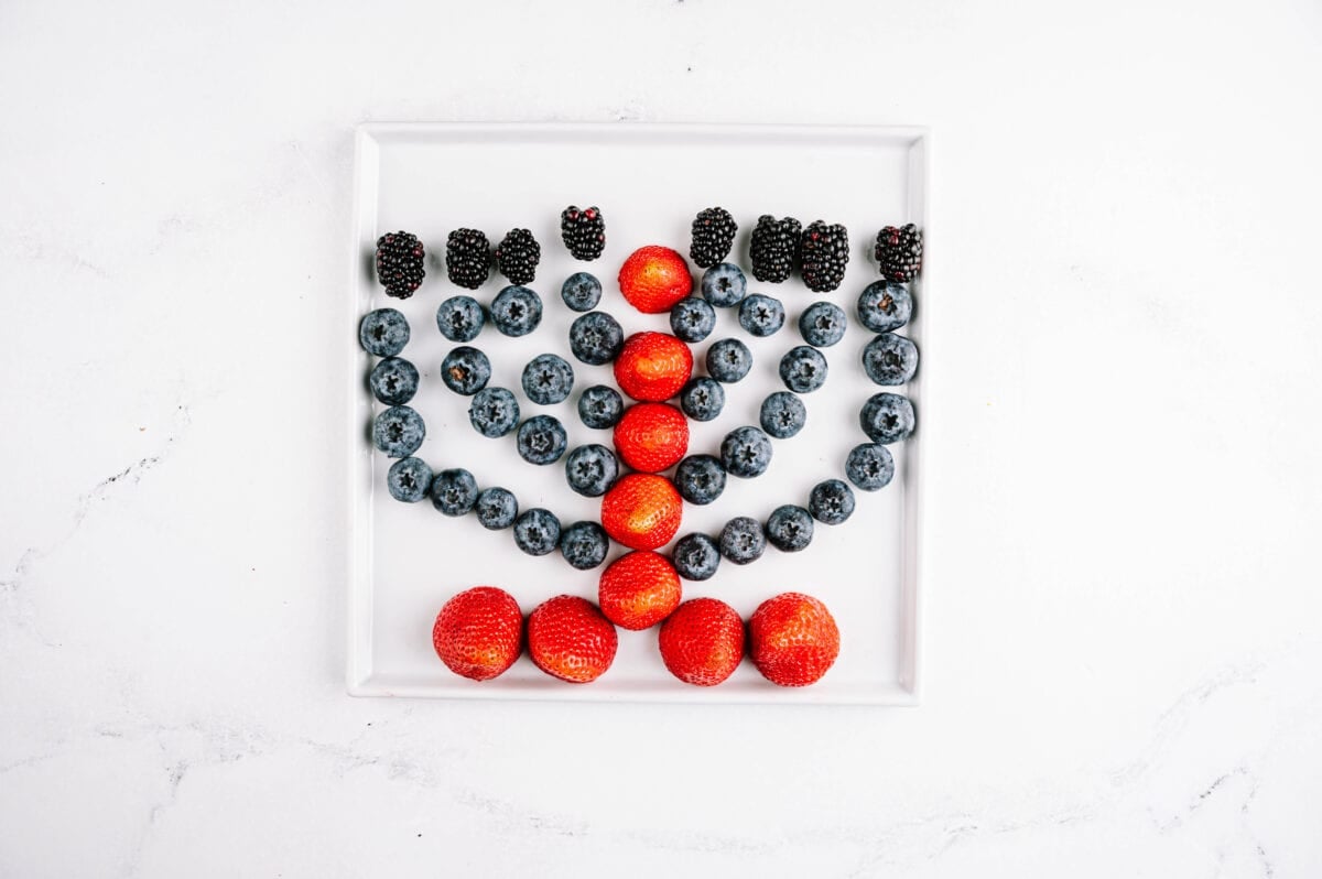 strawberries, blackberries and blueberries on a plate layed out to look like a menorah