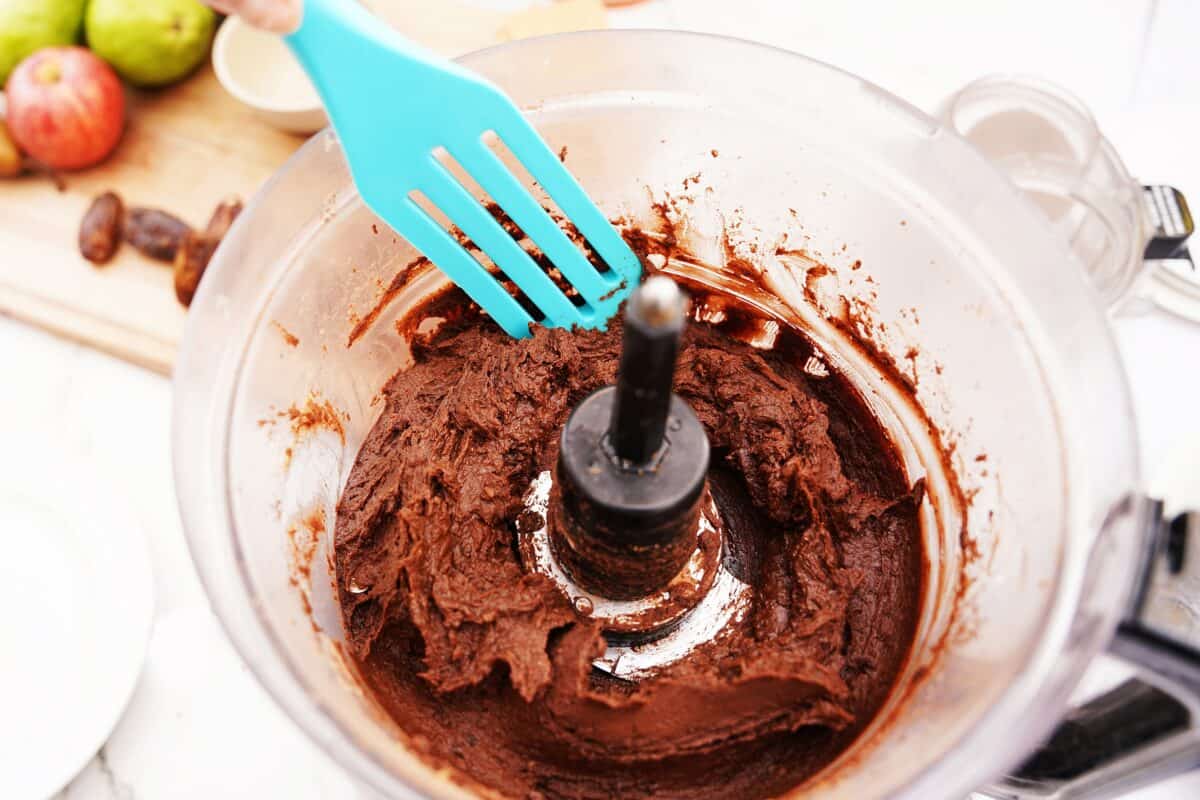 spatula scraping down the sides of a food processor for chocolate hummus recipe