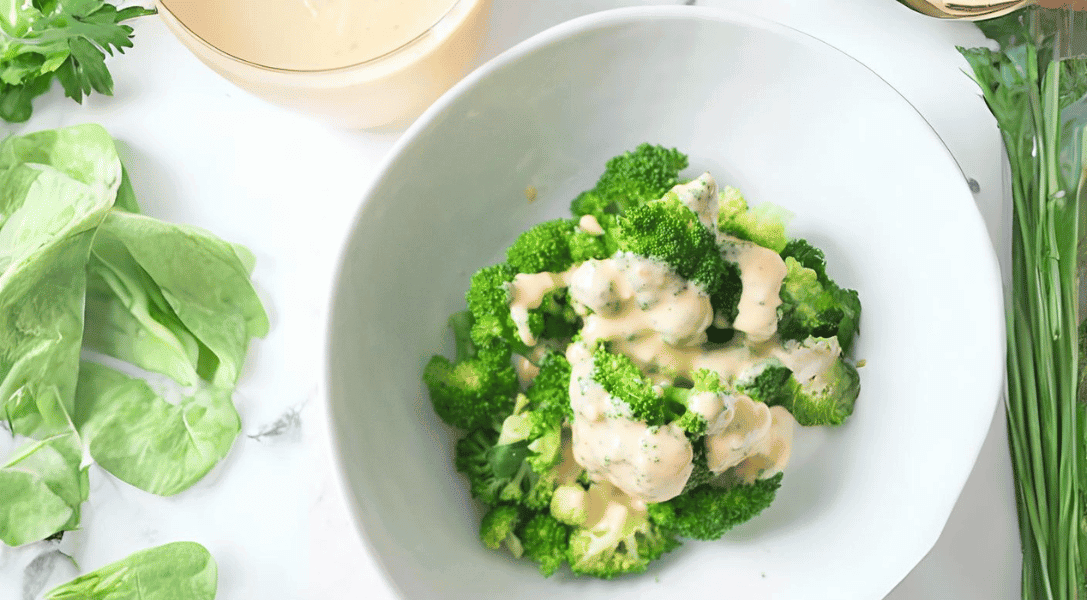 Bowl of broccoli with cheese sauce with cheese sauce in background