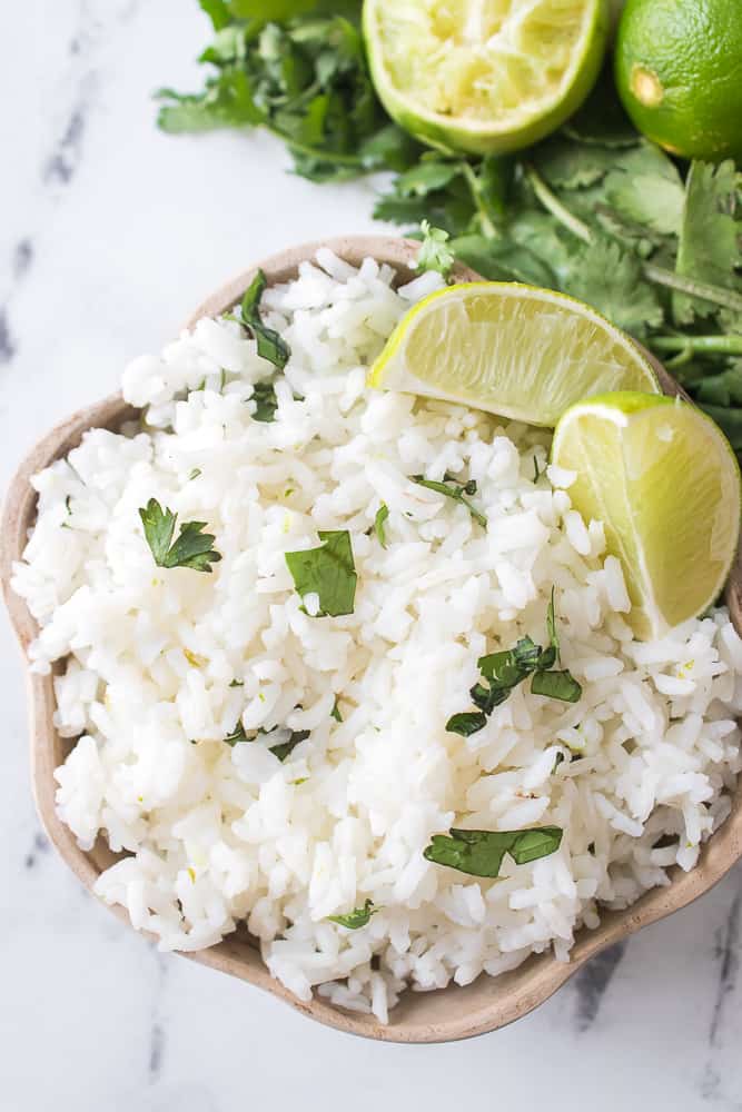 wooden bowl filled with cilantro rice recipe served with lime slices and cilantro