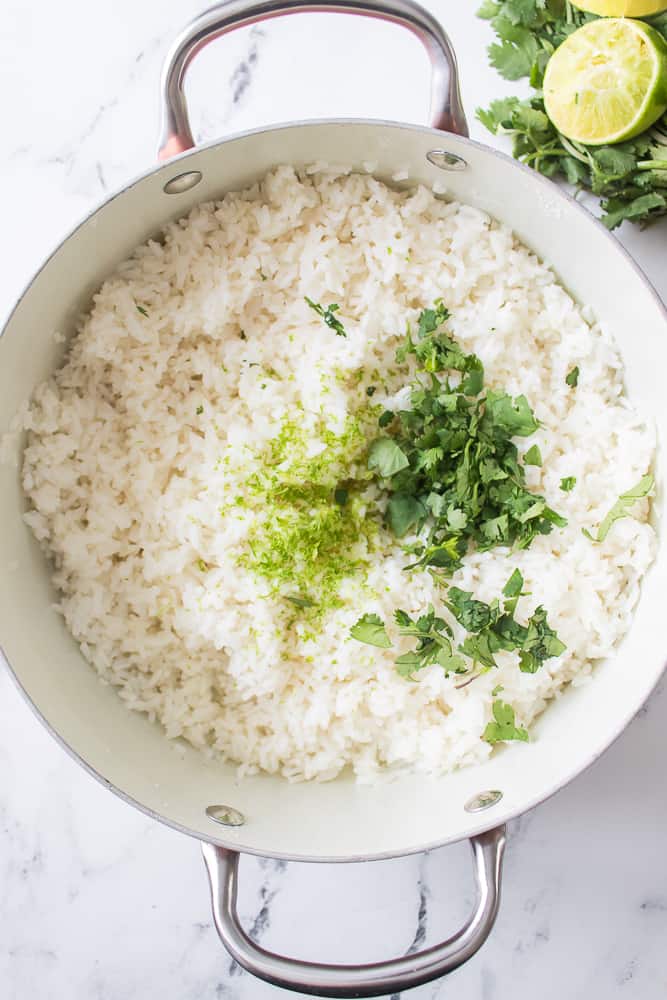 lime zest and cilantro added to white rice in pan