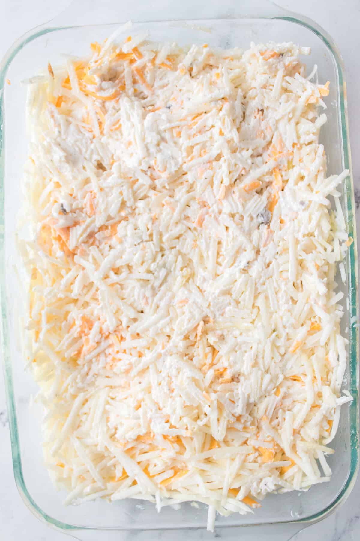 glass casserole dish with unbaked funeral potatoes