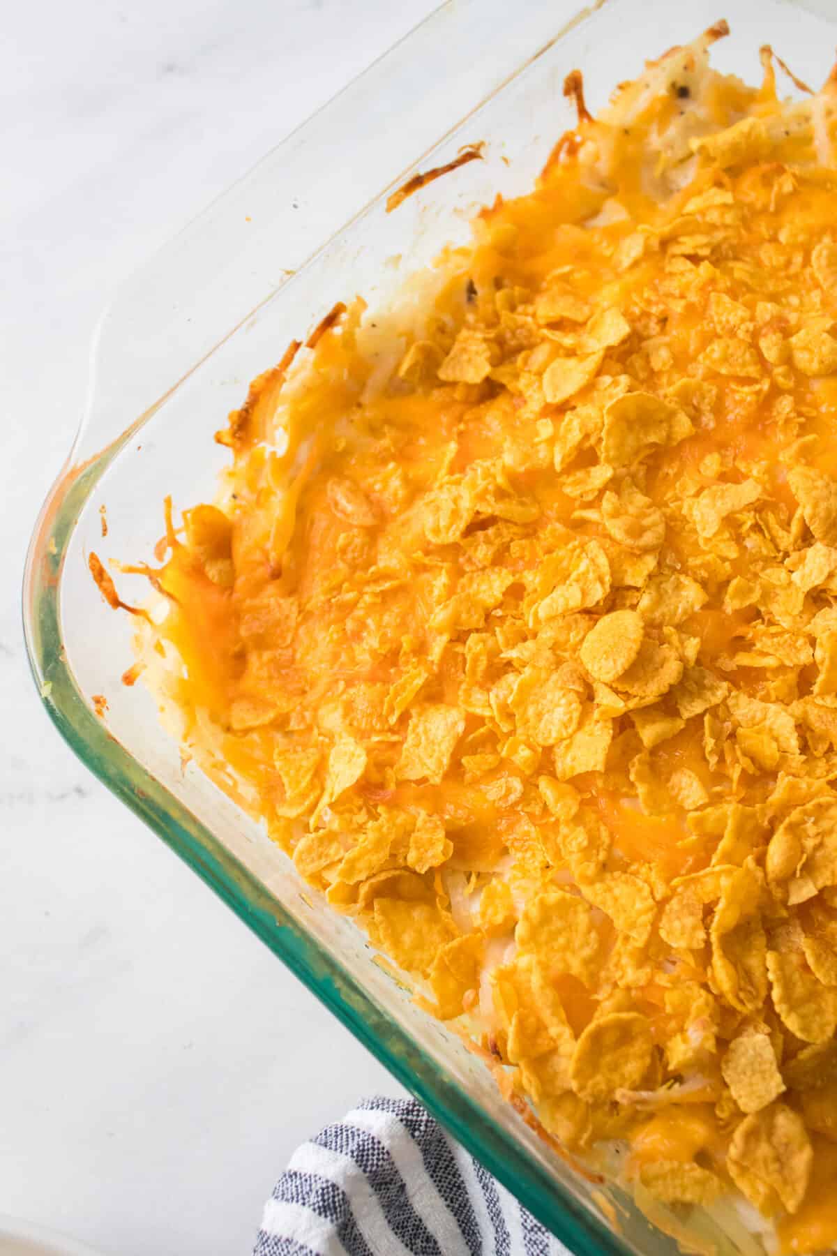 upclose vertical image of funeral potatoes in glass casserole dish