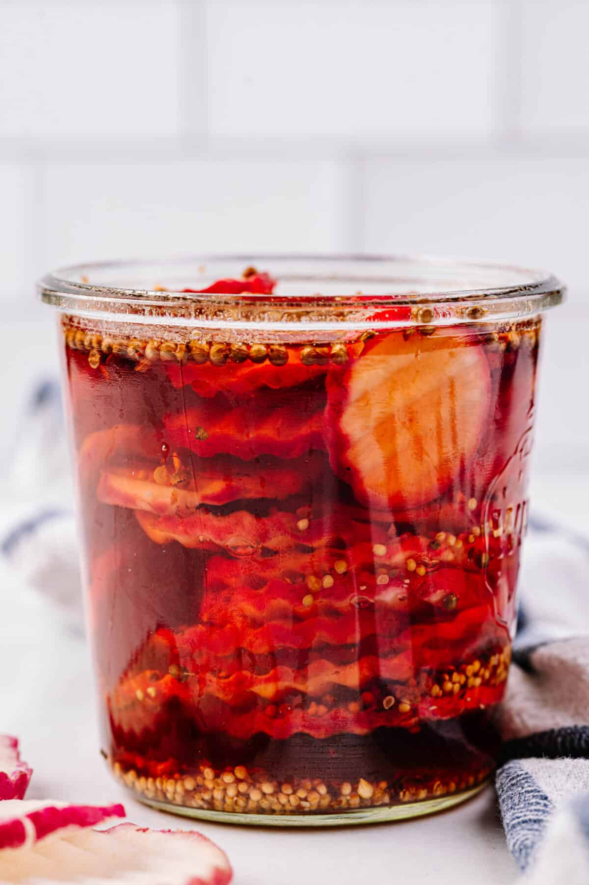 vertical head on shot of pickled radish in glass jar