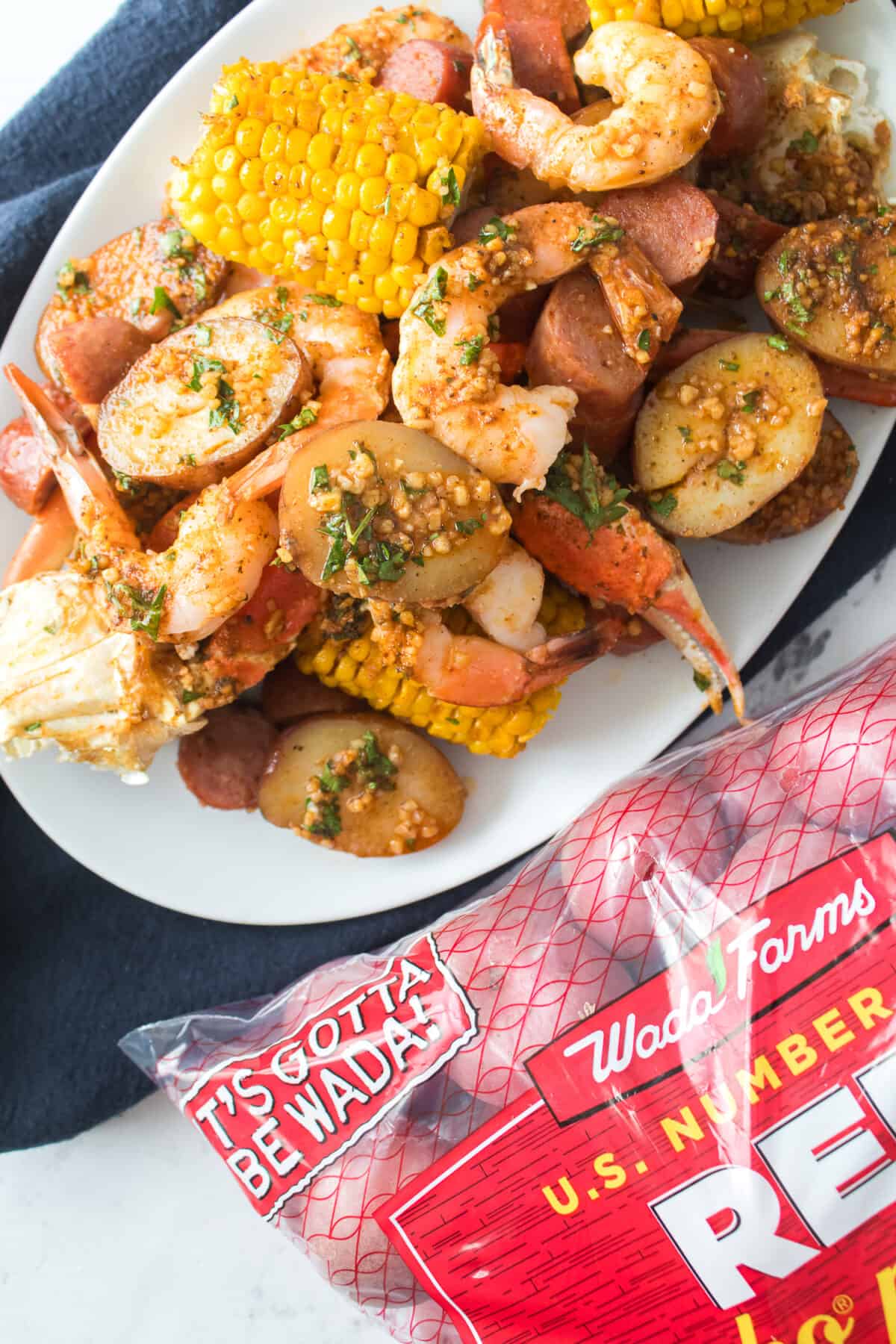 shot of seafood boil on serving platter with bag of wada farms red potatoes