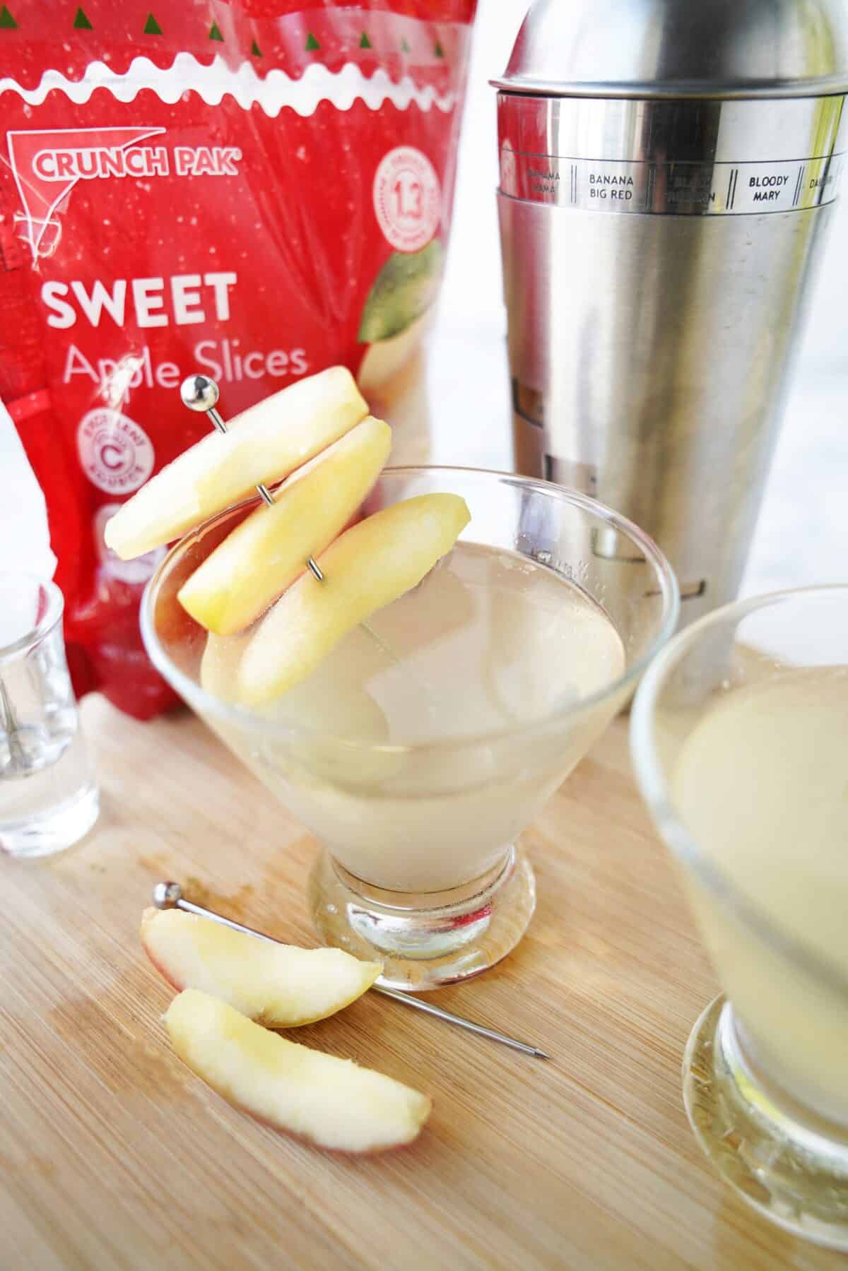 close up shot of apple martini in cocktail glass garnished with apple slices