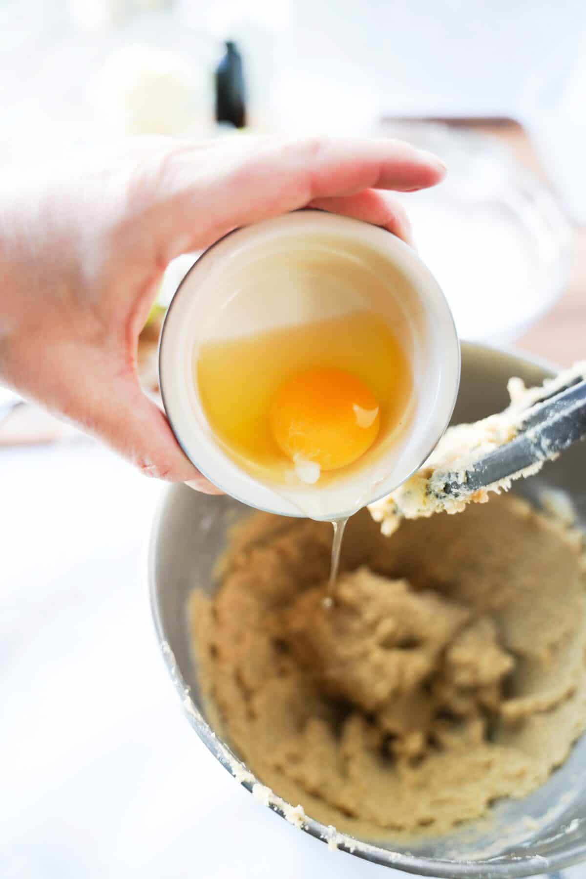 egg being added to stand mixer with butter and sugar