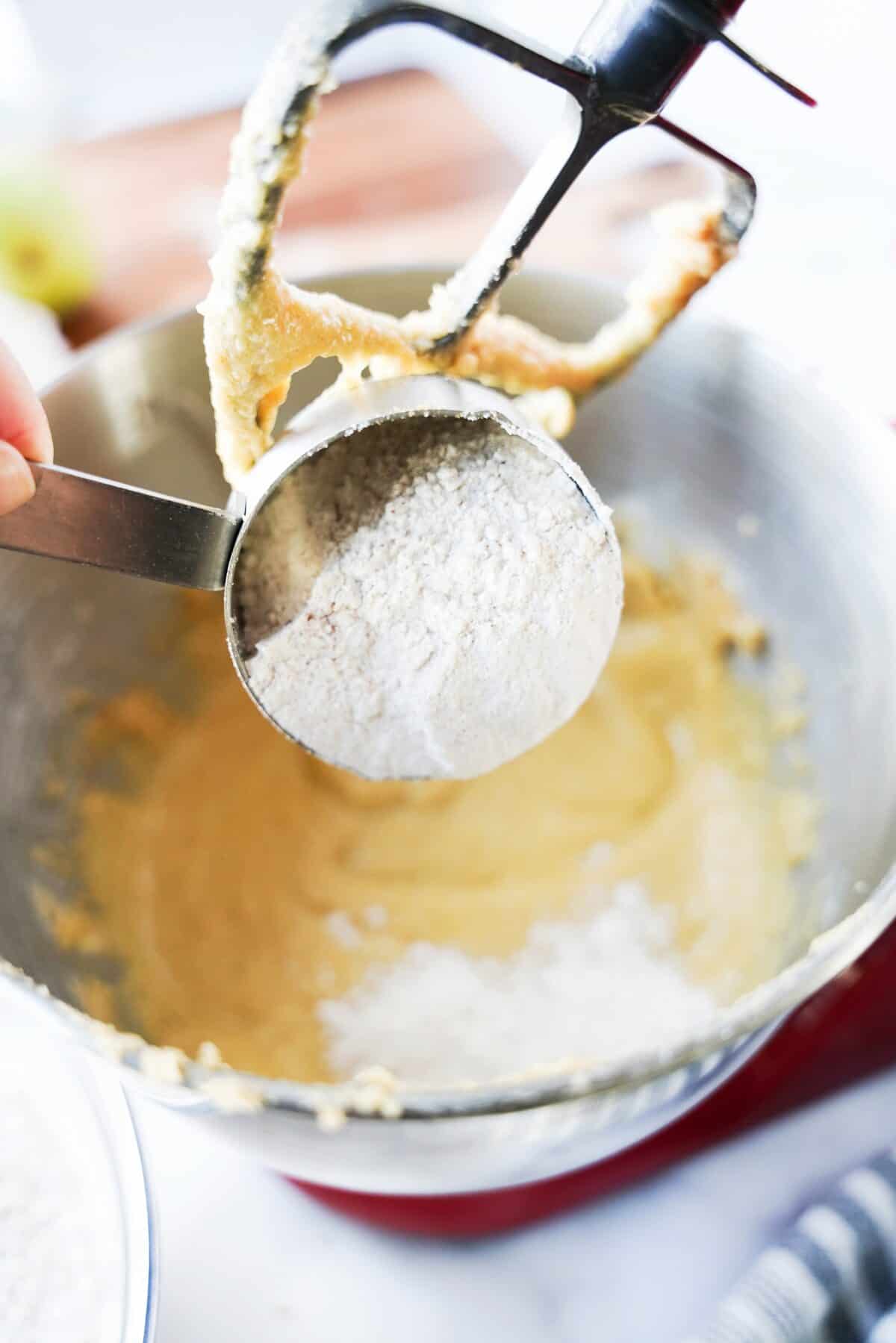 flour being added to stand mixer with butter and sugar thats been creamed together