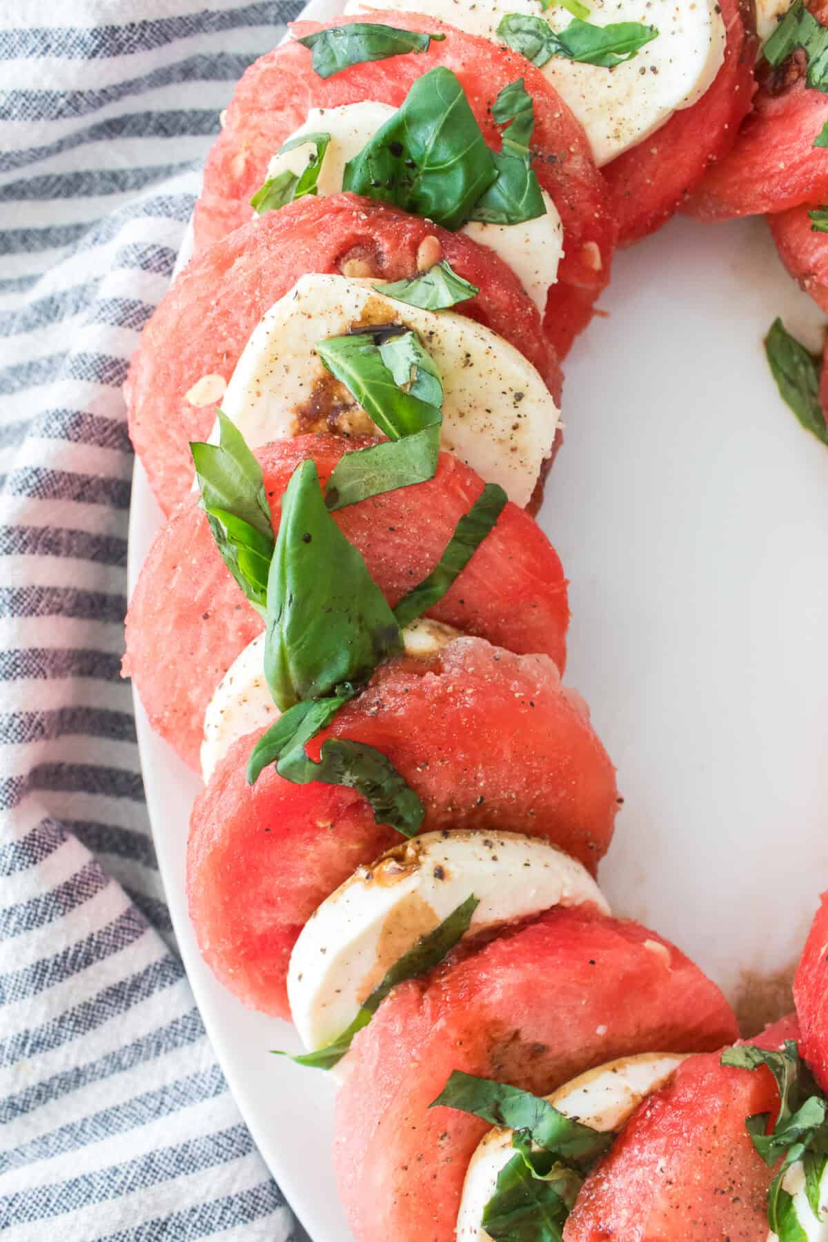 close up vertical shot of watermelon caprese on serving platter topped with balsamic glaze