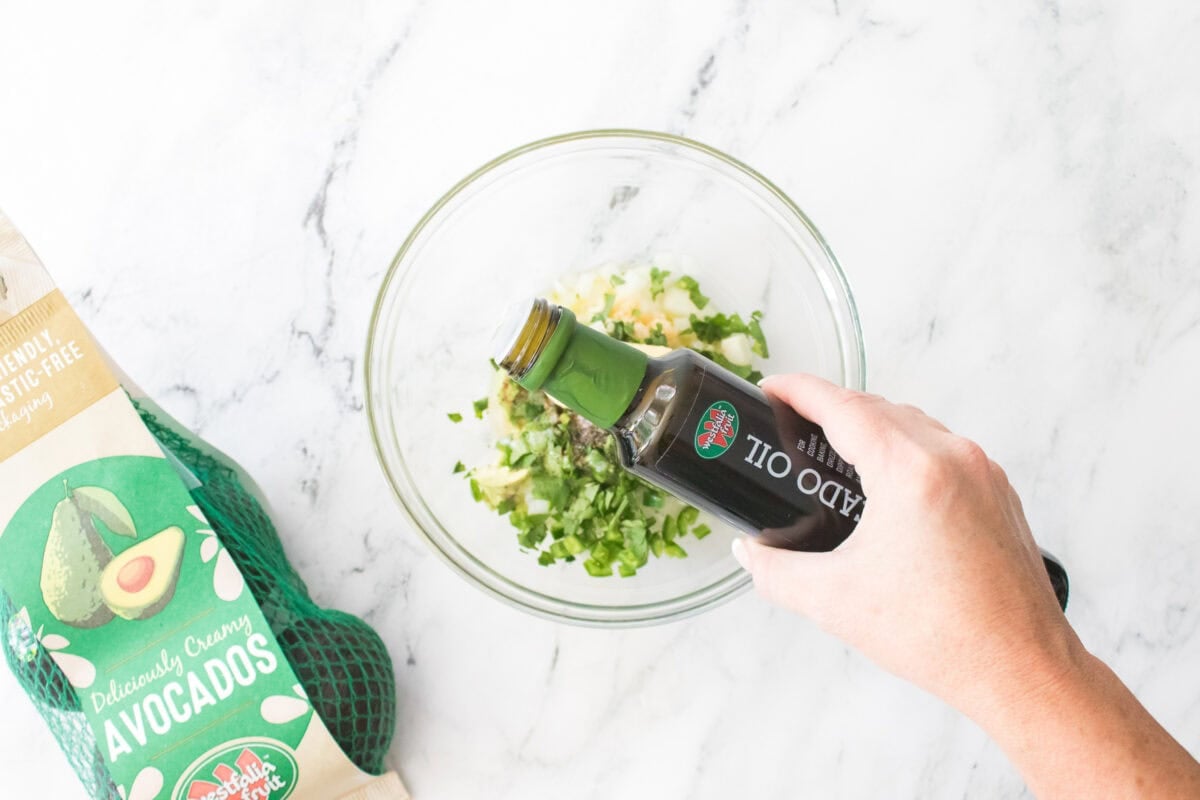 hand pouring bottle of Westfalia fruit avocado oil into bowl