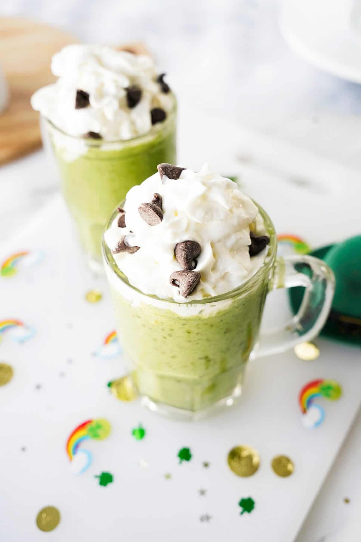 45 degree shot of avocado mint green smoothie in glass mug topped with whipped cream and chocolate chips
