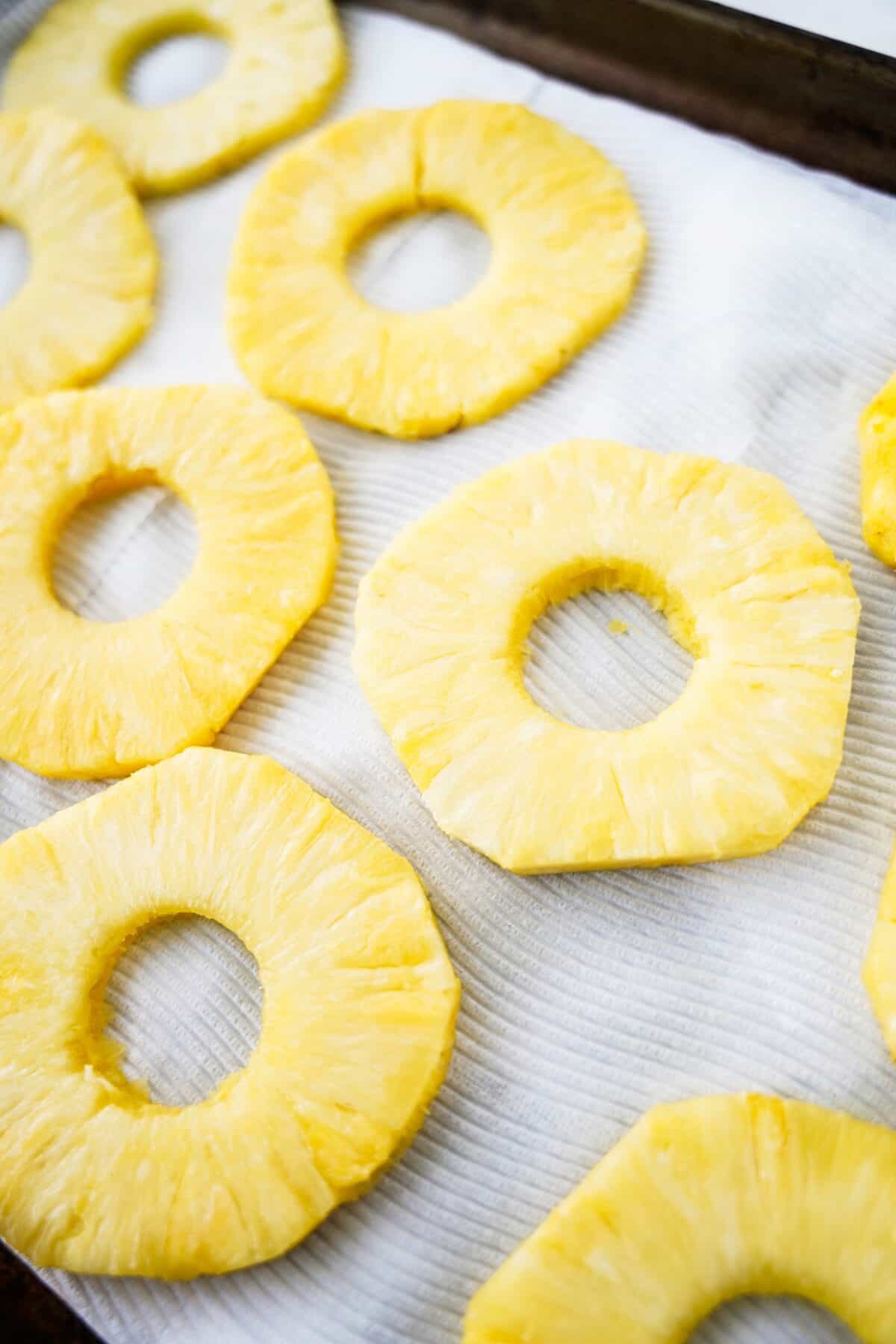 overhead shot of pineapples on baking sheet with paper towels to dry them out