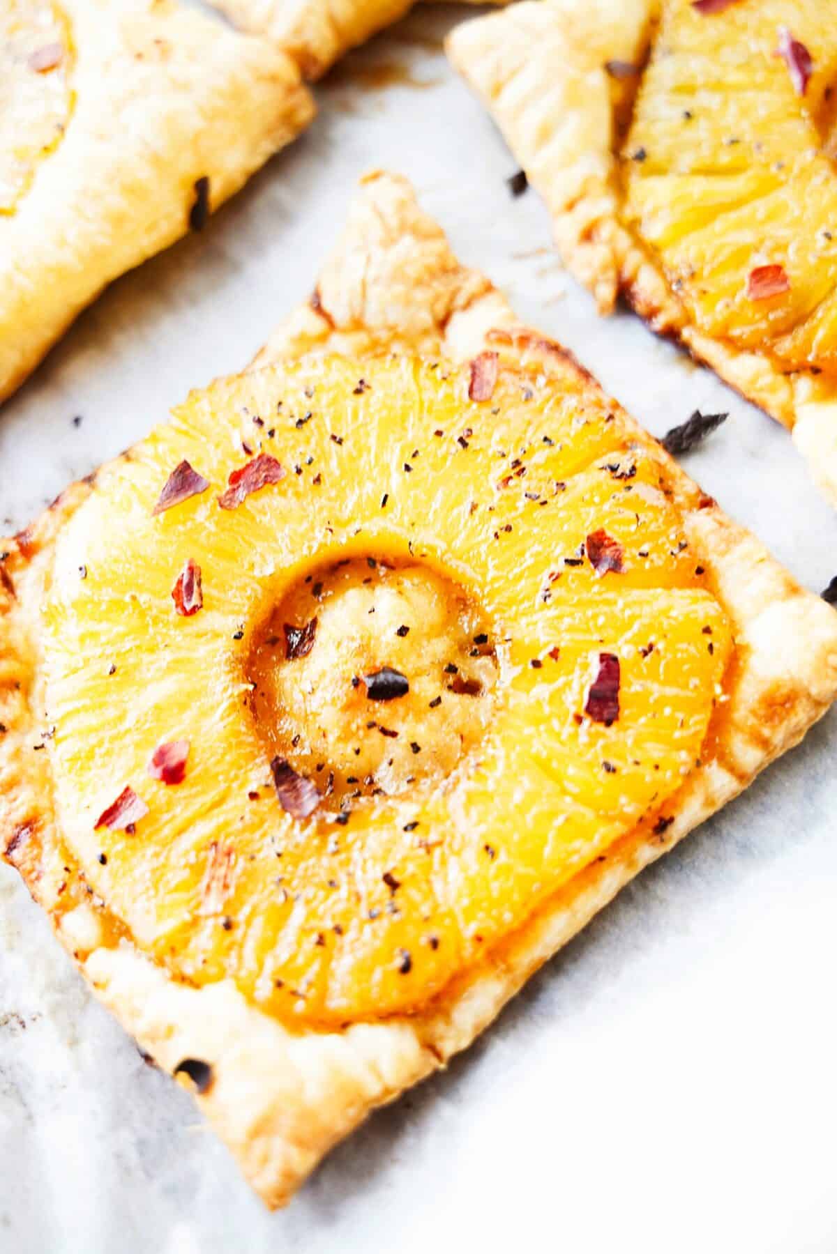 close up vertical shot of spicy pineapple tart topped with crushed red pepper flakes