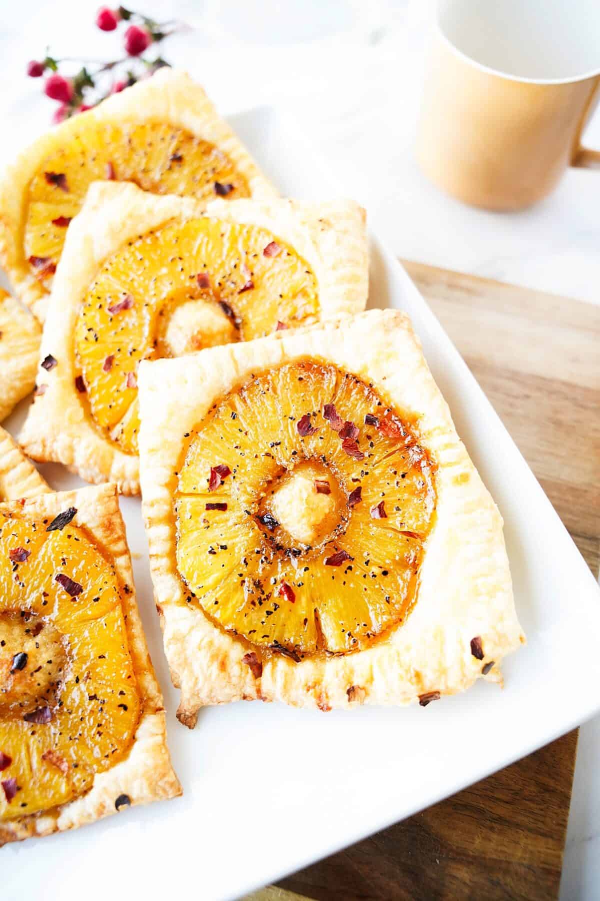 close up vertical shot of spicy pineapple tart on white square plate