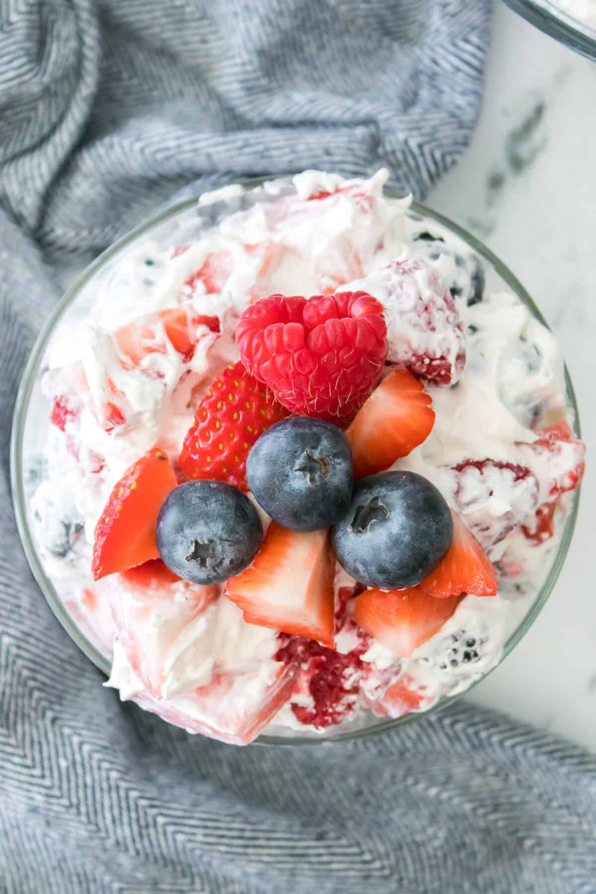 overhead shot of summertime cheesecake fruit salad with raspberry, blueberries and strawberries on top