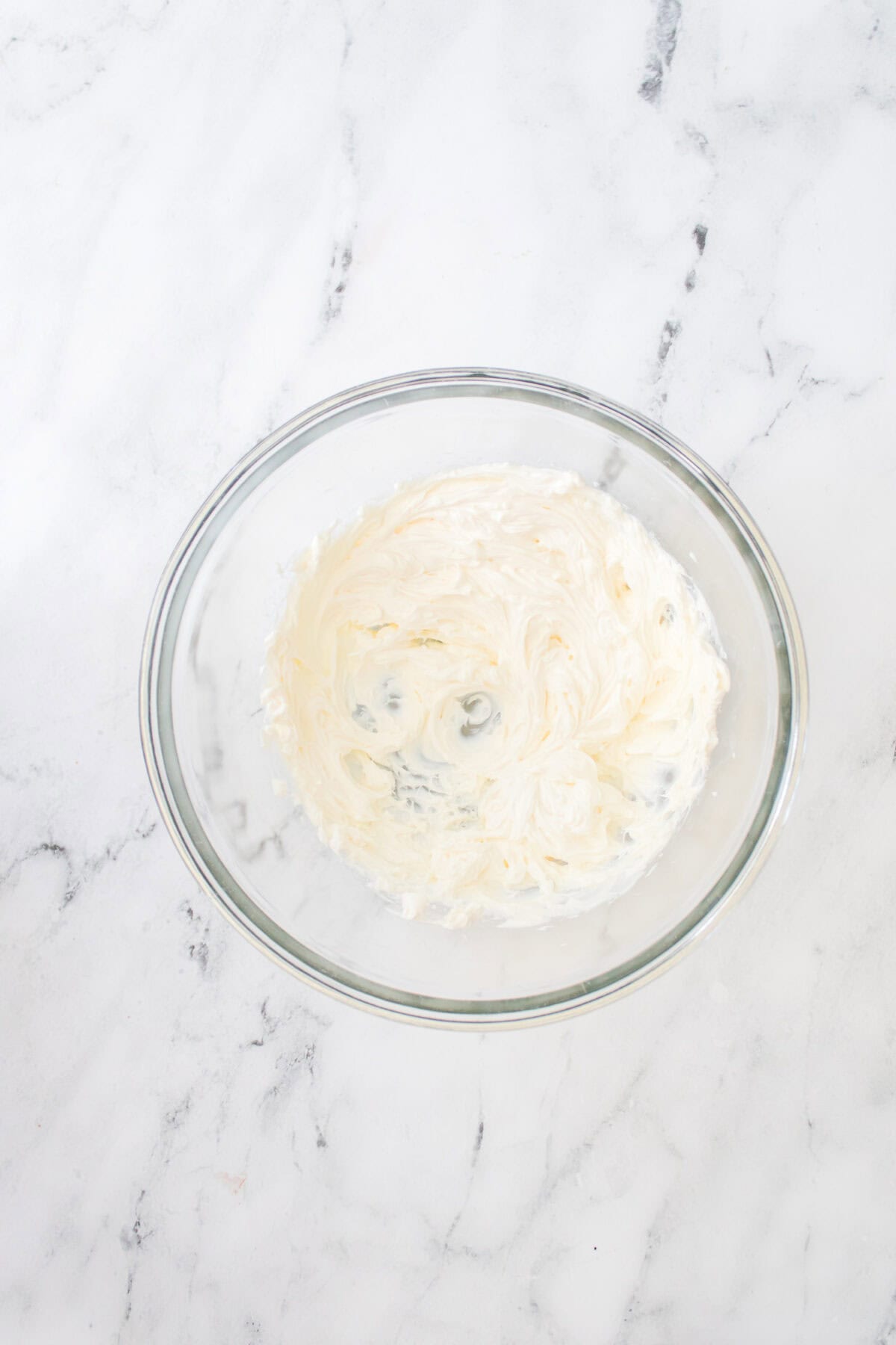 overhead shot of cream cheese blended until smooth in glass bowl