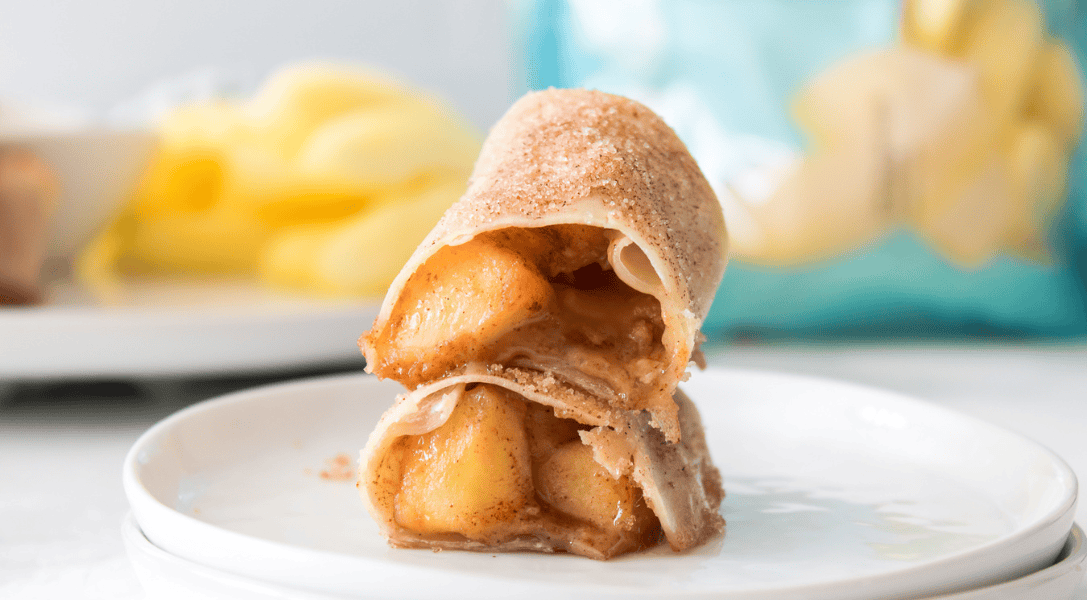horizontal shot of cut open caramel apple egg roll on white plate