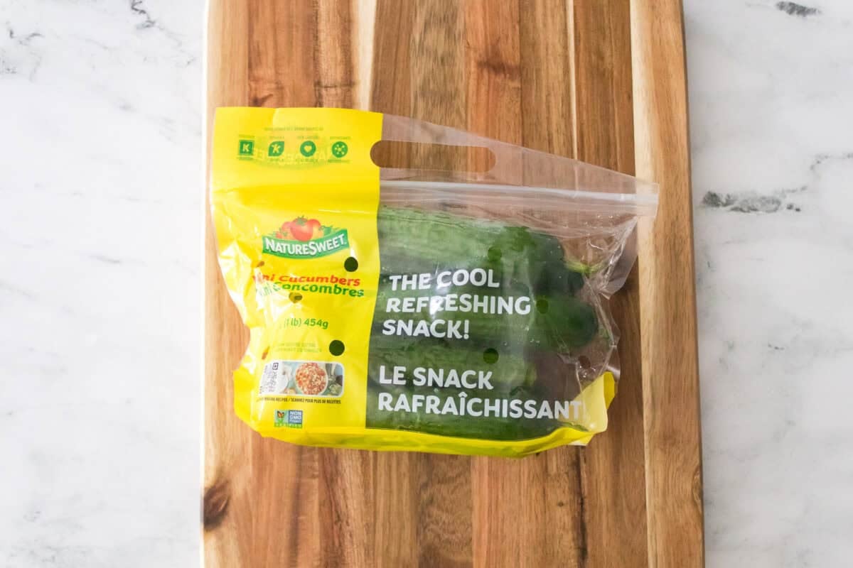 overhead shot of bag of naturesweet mini cucumbers on cutting board