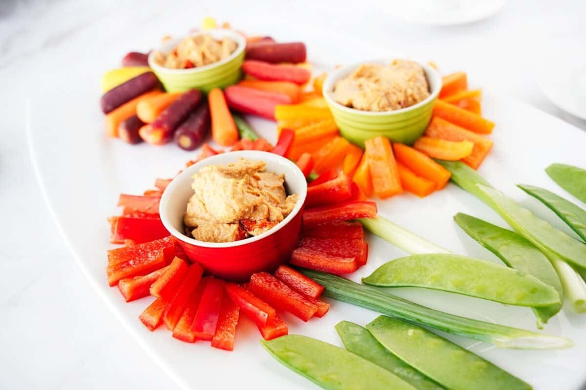 45 degree shot of red bell peppers in focus for a flower veggie tray served with hummus in the center of 3 flowers