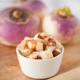 Vertical image of roasted turnips in white bowl