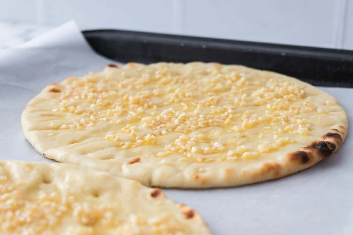 flatbread on baking sheet with olive oil and minced garlic