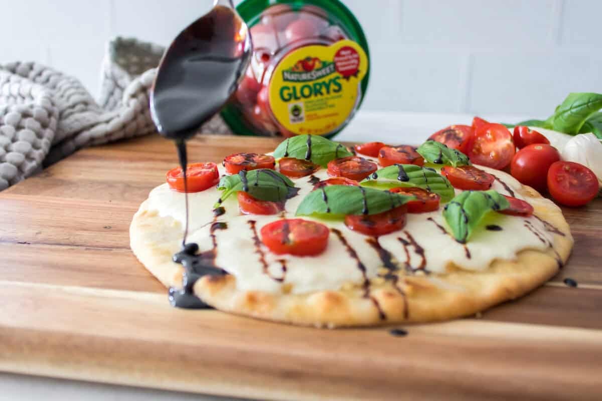 balsamic glaze being drizzled over caprese flatbread