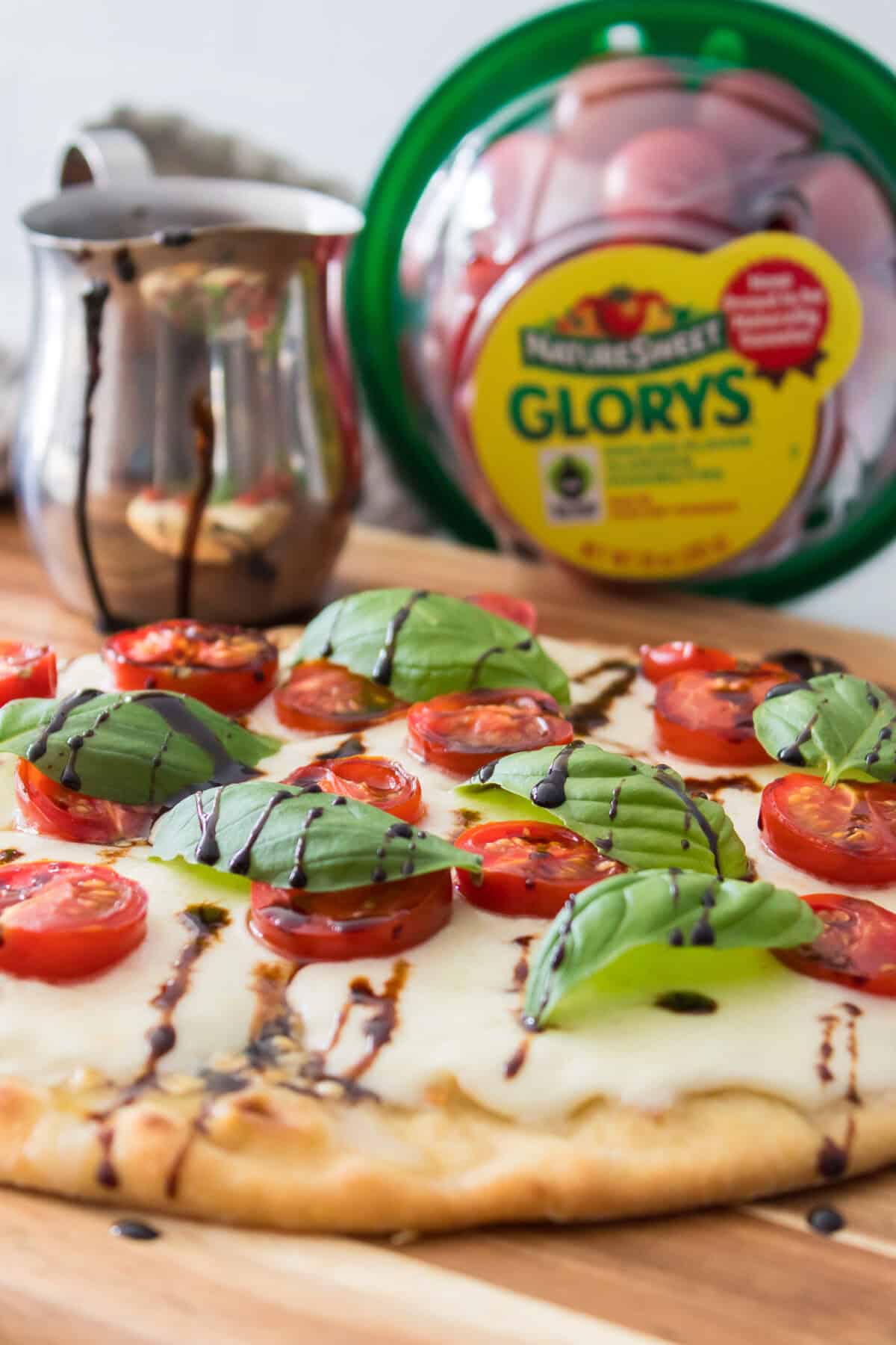head on shot of caprese flatbread with balsamic glaze with naturesweet glorys in background