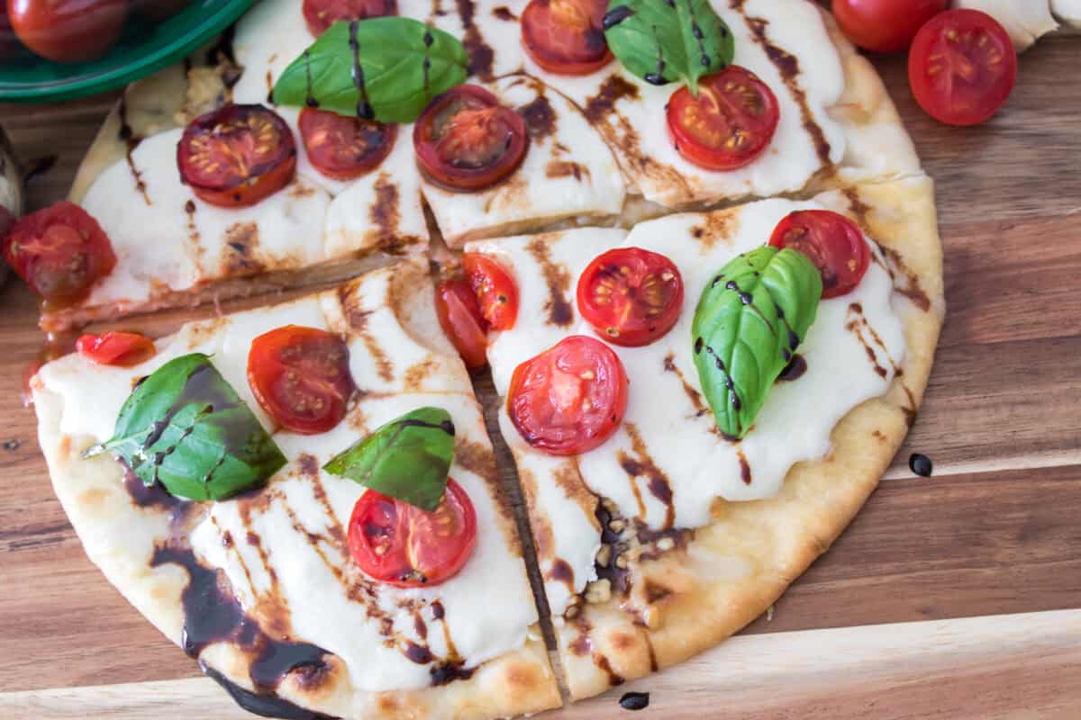 overhead close up shot of caprese flatbread on cutting board