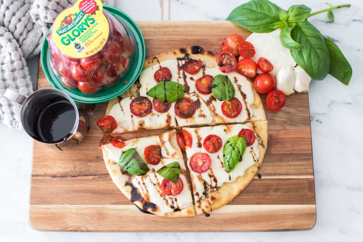 overhead horizontal shot of caprese flatbread cut into 4 slices on cutting board