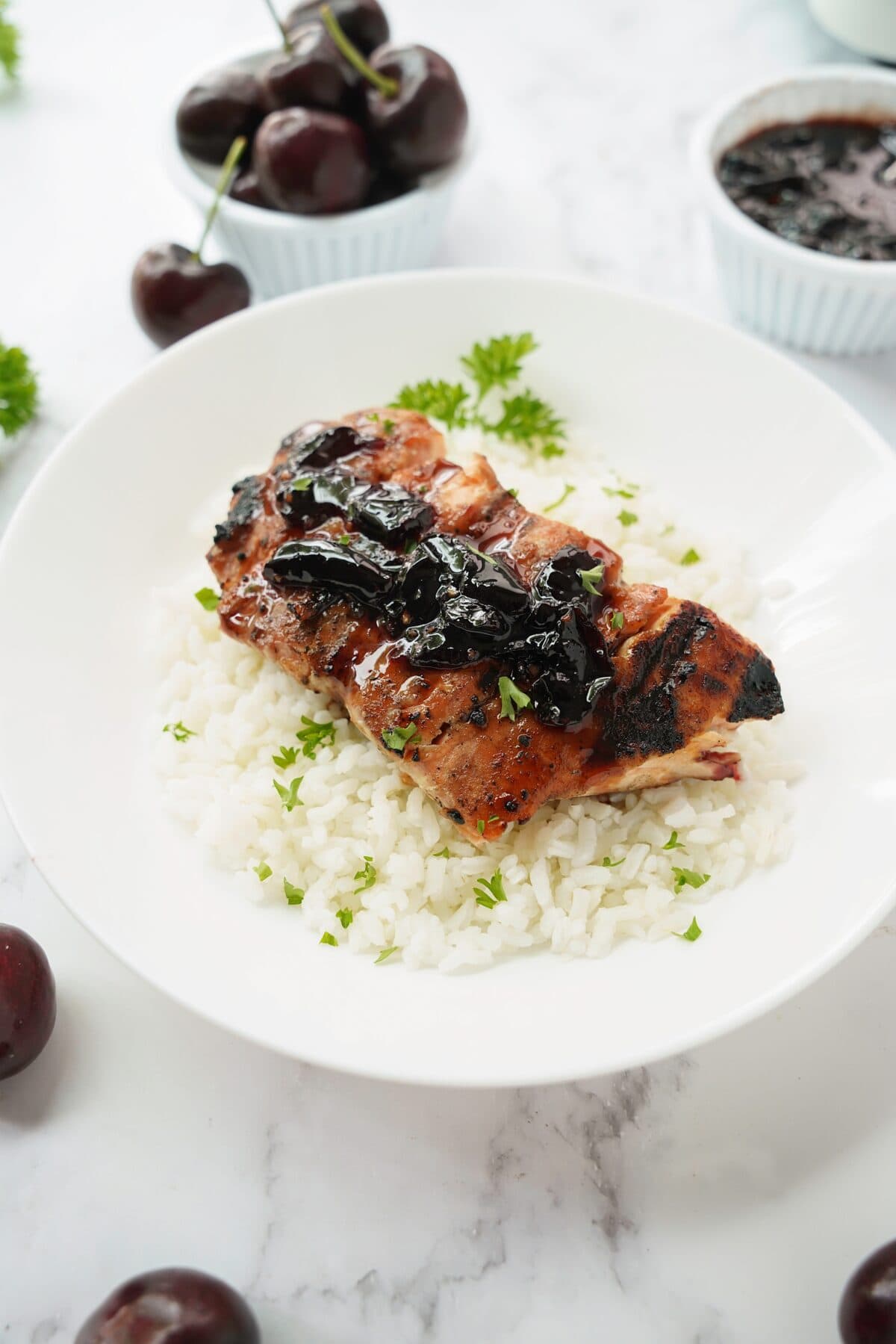 45 degree shot of cherry glazed salmon served over white rice garnished with parsley