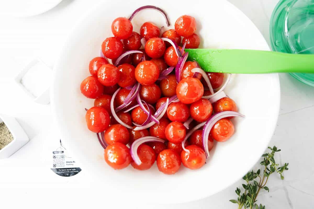 naturesweet glorys tomatoes, sliced red onion tossed in olive oil and hot honey in white bowl
