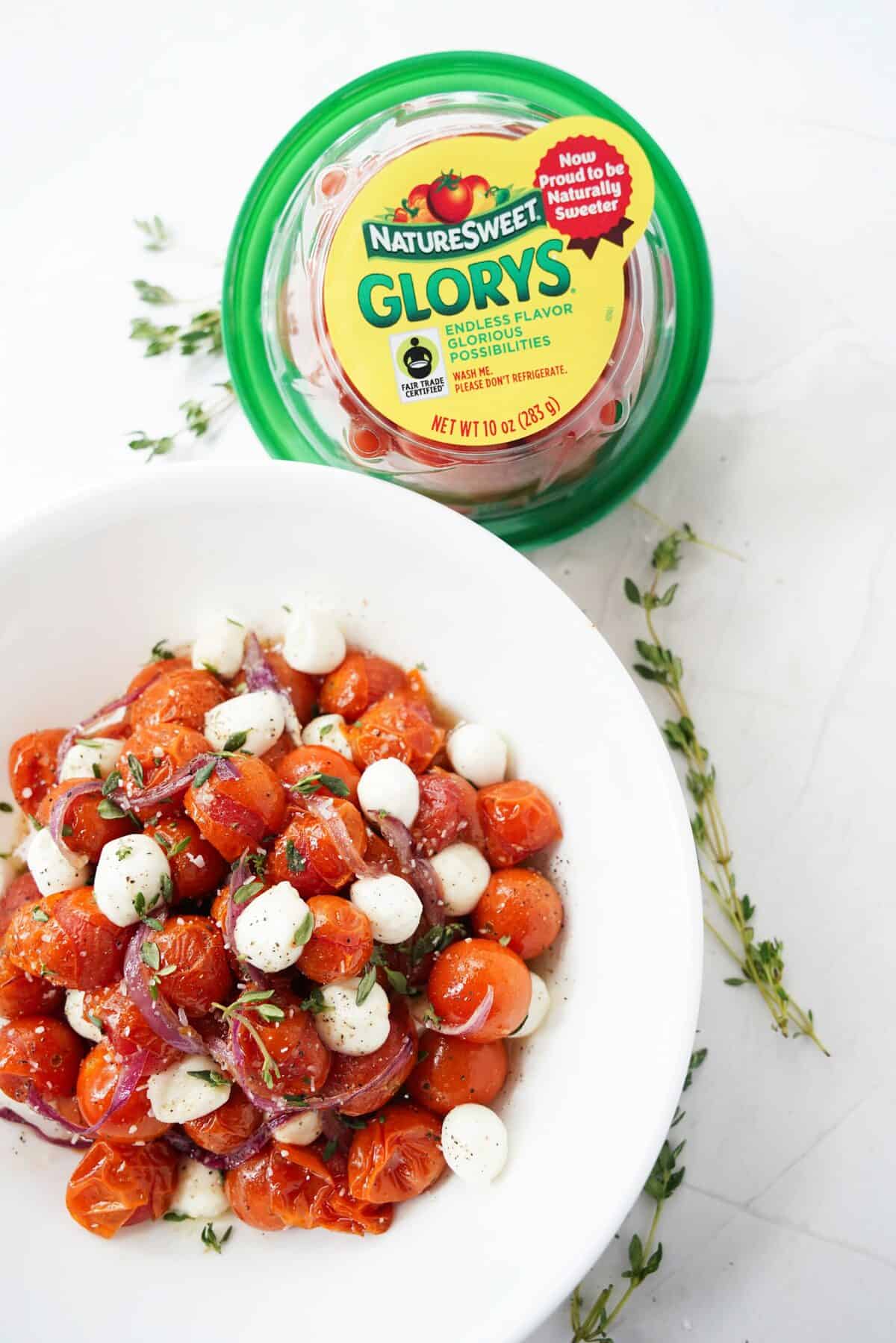 overhead shot of hot honey roasted cherry tomatoes and onions with mozzarella pearl balls and garnished with fresh thyme