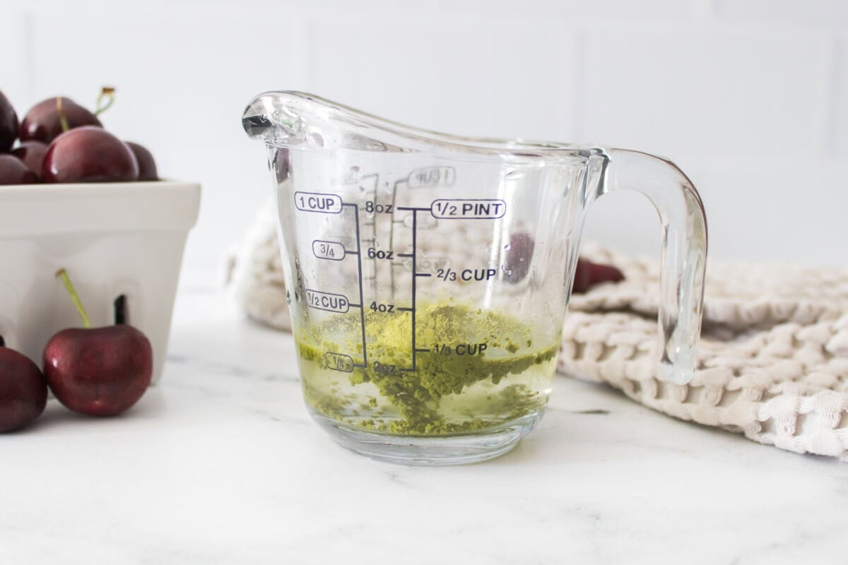 matcha in measuring cup with handle in water before stirring