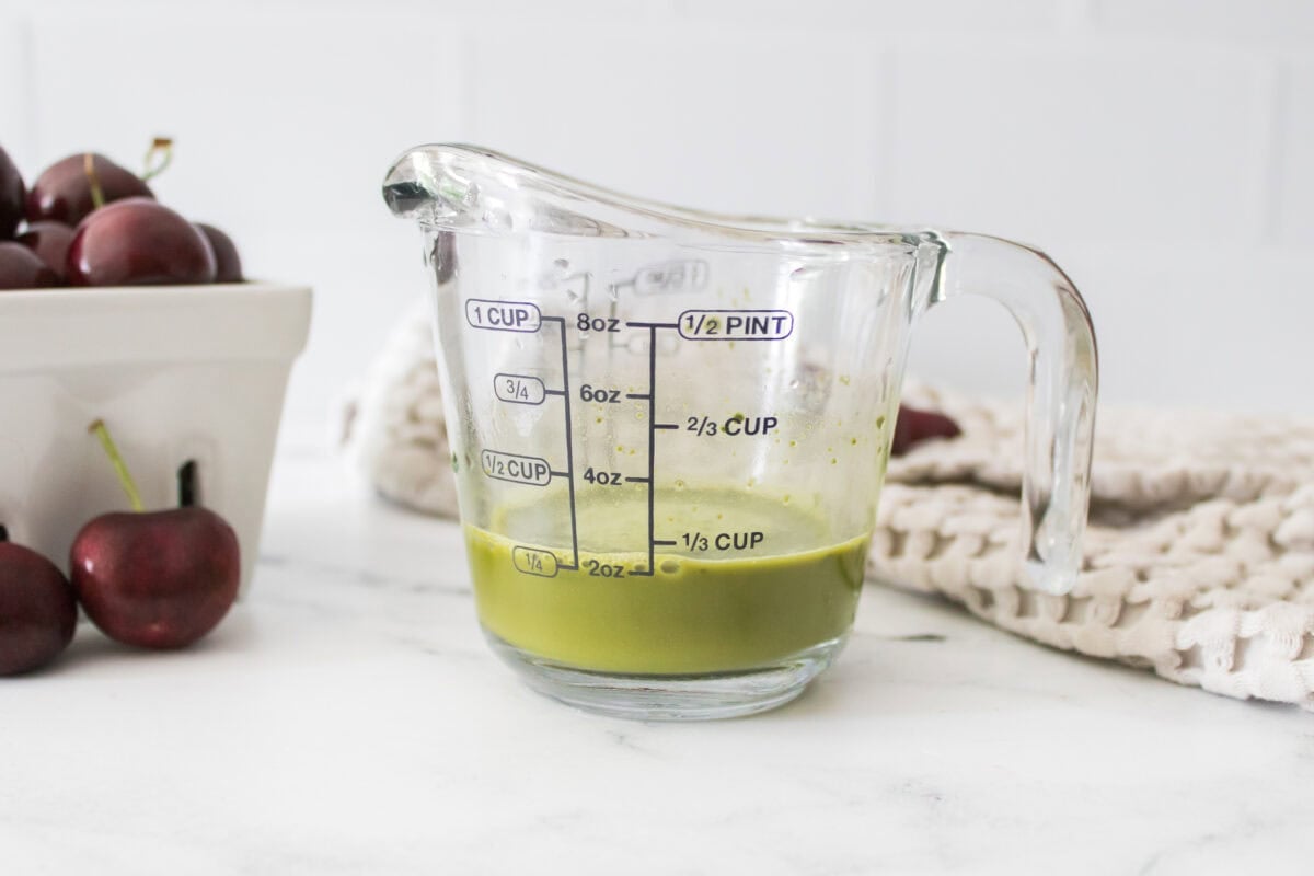 head on shot of matcha mixed with water in measuring cup with handle