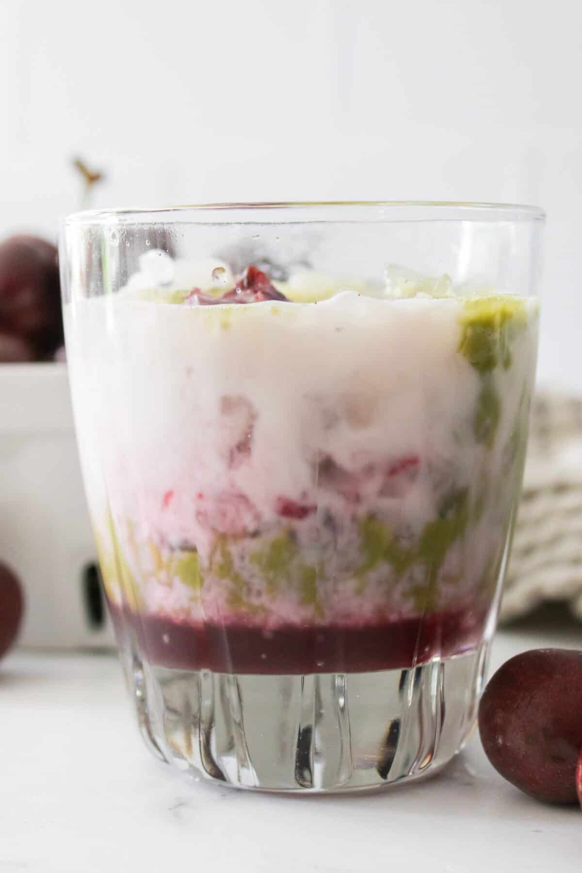 close up vertical shot of layers of cherry matcha: cherry syrup, milk and matcha