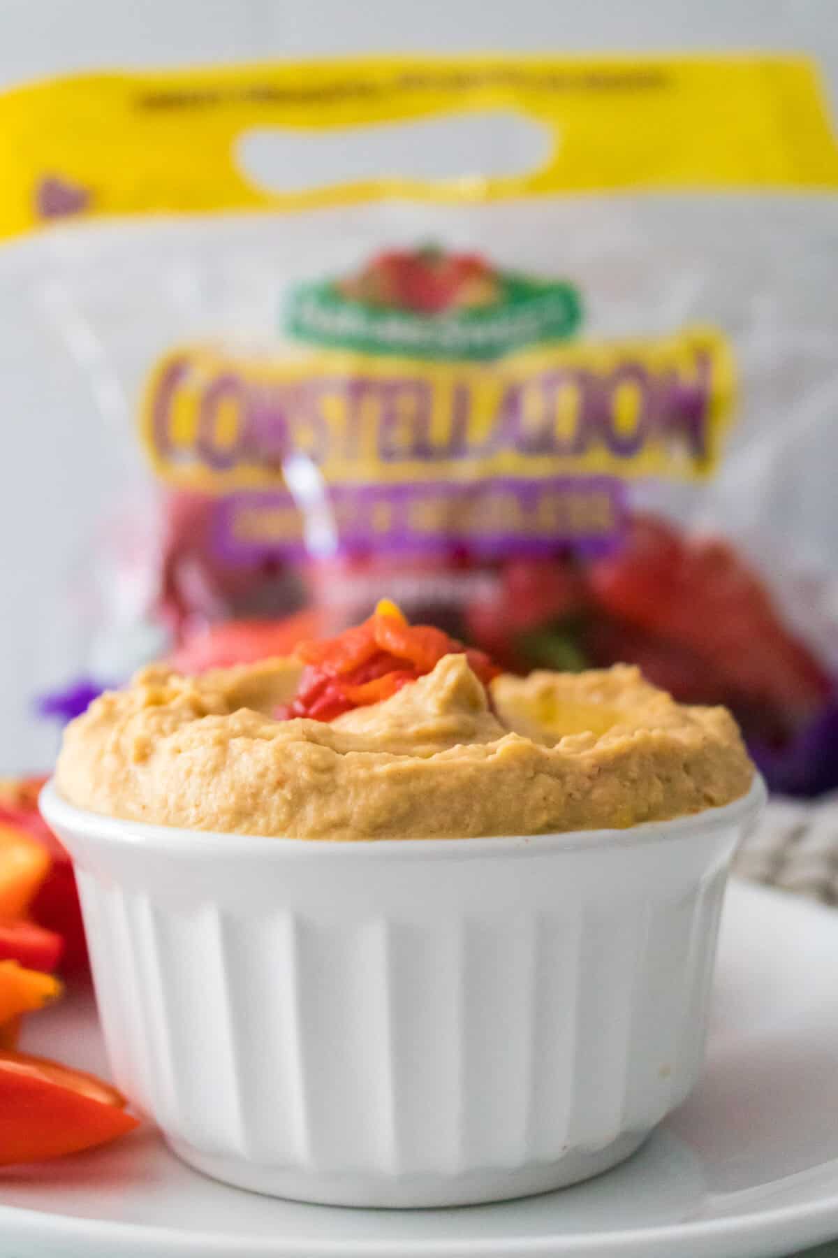 vertical head on shot of roasted pepper hummus garnished with roasted peppers