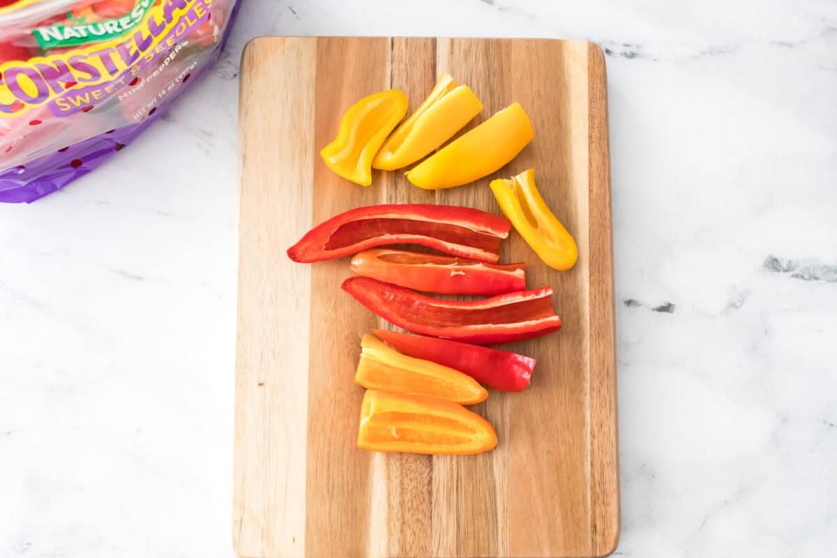 overhead shot of naturesweet sweet and seedless mini peppers cut open on wooden cutting board