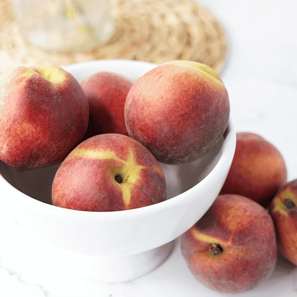 Bowl of peaches on white countertop