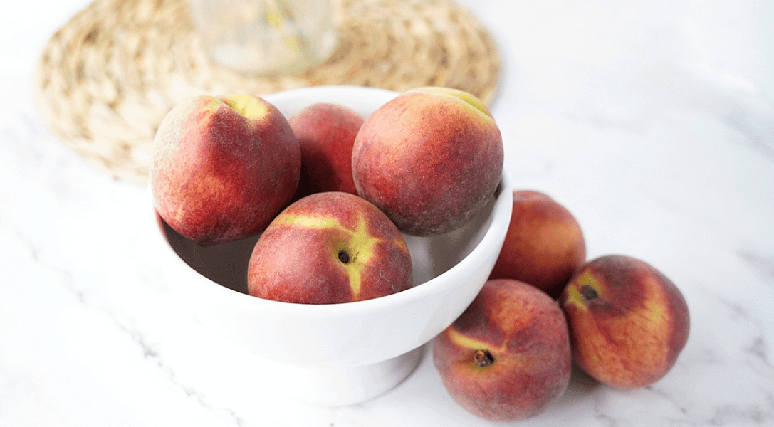 Bowl of peaches on white countertop