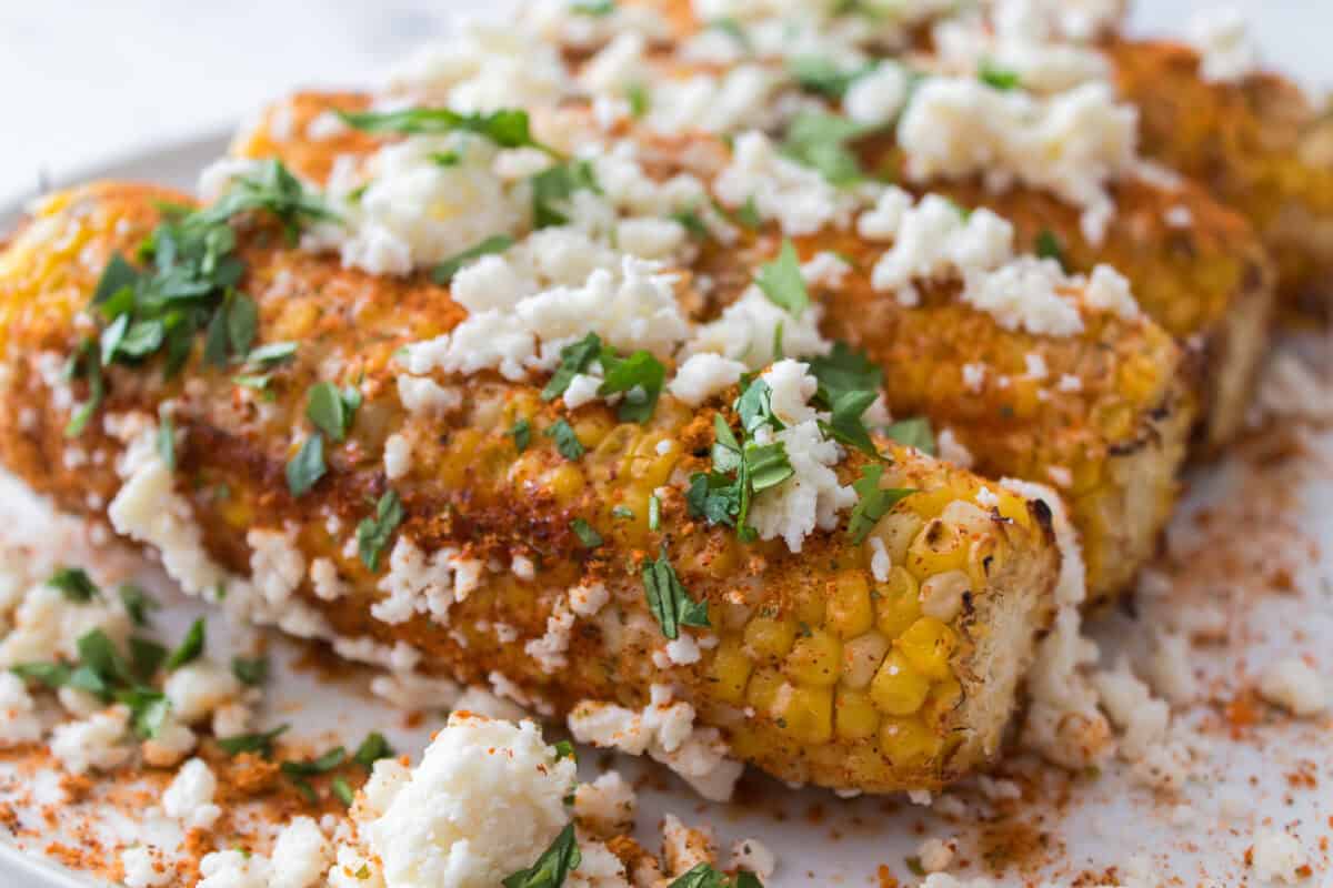 close up shot of elote corn topped with cojita cheese and cilantro